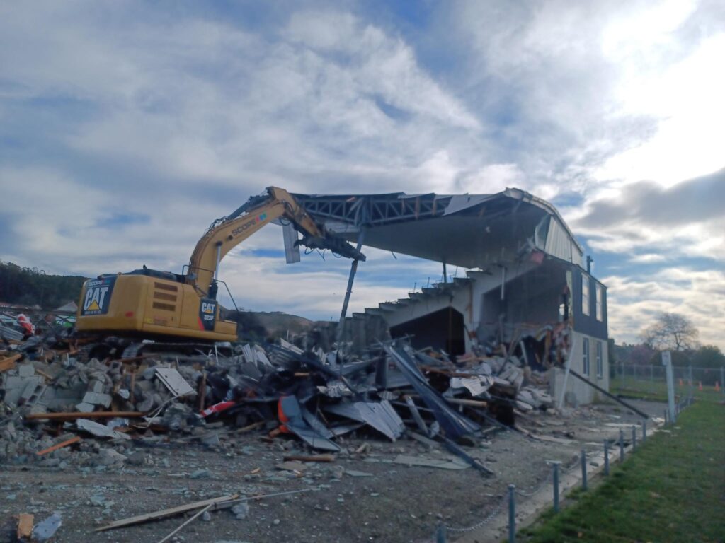 image of Scope Group excavator demolishing rugby grandstand in North Otago, New Zealand