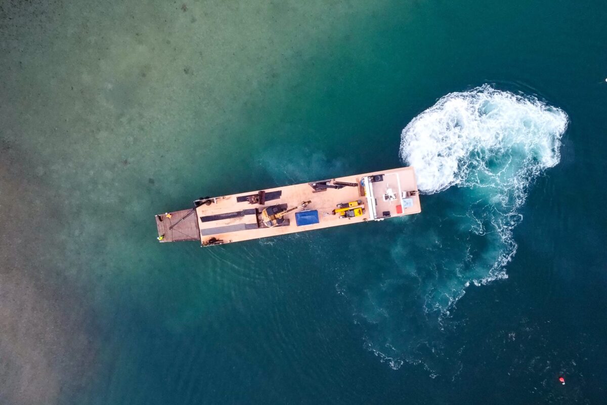 aerial drone image of Scope Group excavation machinery being delivered by boat at demolition and deconstruction project at Becks Bay, Marlborough, NZ