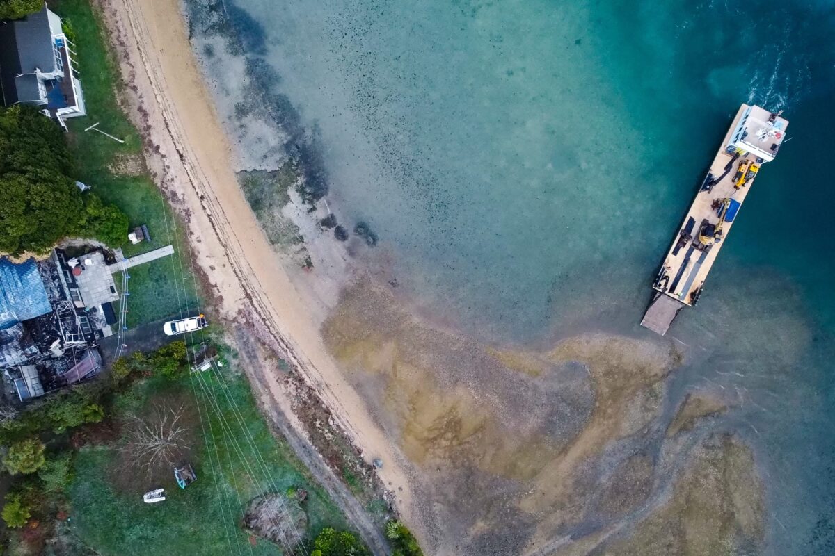 aerial drone image of Scope Group excavation machinery being delivered by boat at demolition and deconstruction project at Becks Bay, Marlborough, NZ