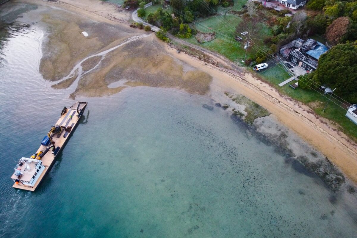 drone image of Scope Group excavation machinery being delivered by boat at demolition and deconstruction project at Becks Bay, Marlborough, NZ